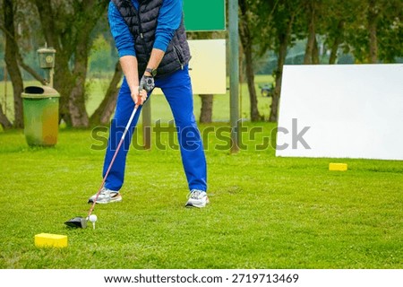 Low angle view on golfer as swing, strong hit golf ball, moment before starting the golf swing. He shot with club on course, taking a shot to fairway.