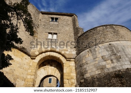 Low angle view on a massive, stone castle, featuring round towers, old mullion windows and a fortified gate formerly equipped with a harrow, in Cordes-sur-Ciel, a medieval village in Southern France