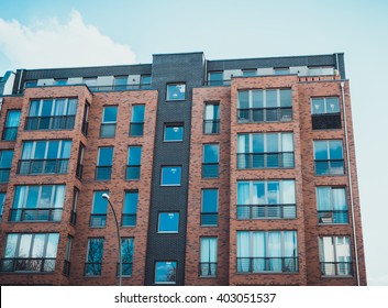 Low Angle View On Modern Residential Brick Apartment Building Exterior With Large Windows And Penthouse