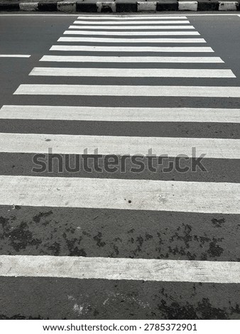 Low angle view of a pedestrian crossing on an asphalt road, emphasizing road safety, urban transportation, and public infrastructure.