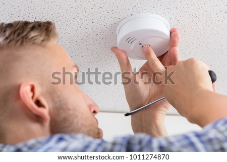 Low Angle View Of A Person's Hand Installing Smoke Detector On Ceiling Wall At Home Stock photo © 