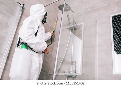 low angle view of pest control worker spraying pesticides with sprayer in bathroom - Shutterstock ID 1135151402