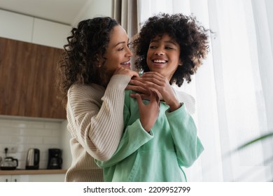 Low Angle View Of Pleased African American Woman Smiling While Hugging Joyful Preteen Daughter