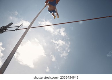 Low angle view pole vaulter clearing bar