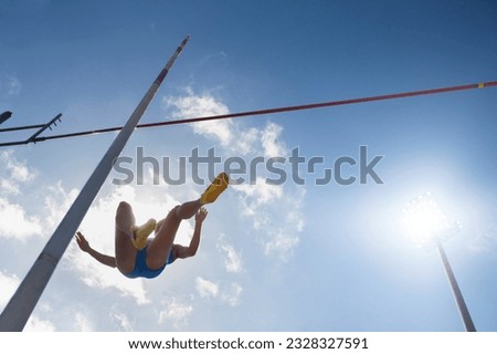 Low angle view pole vaulter clearing bar