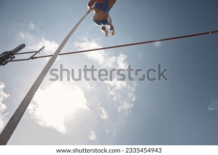 Low angle view pole vaulter clearing bar