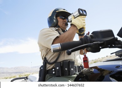 Low Angle View Of A Police Officer Looking Through Radar Gun