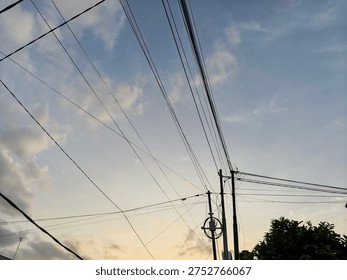 Low angle view of power lines against a soft pastel sunset sky