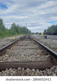 Low angle view of a railway switch with railroad tracks leading into the distance under a partly cloudy sky in a rural railway yard.