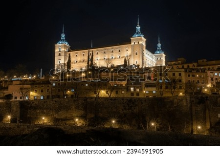 Low angle view of the Real Alcazar of Toledo, Spain (today a military museum) illuminated at night above the houses and walls. UNESCO World Heritage Site. Concept cultural heritage of Spain
