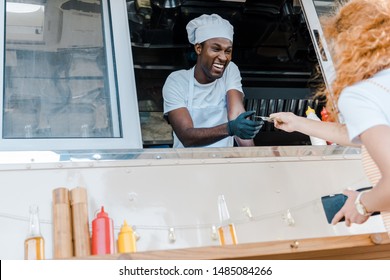 Low Angle View Of Redhead Girl Giving Cash To Happy African American Man In Food Truck 