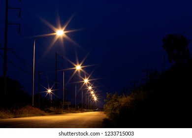 Low angle view of a row of bright orange lanterns on a rural street in the dark.