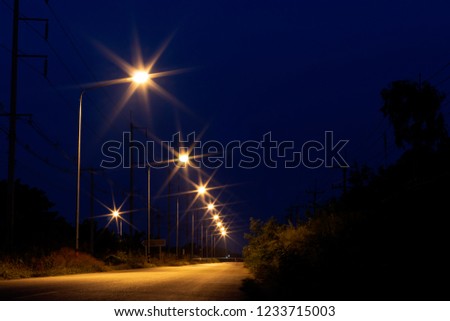 Low angle view of a row of bright orange lanterns on a rural street in the dark.