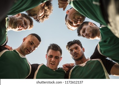 Low angle view of rugby players in circle against clear sky discussing their tactics. Team of rugby player in huddle between the match. - Powered by Shutterstock