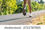 Low angle view of runner feet while running on road. Outdoor fitness, endurance training, healthy lifestyle and sport activity concept.