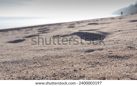Low angle view of a sandy beach of Lake Ontario while a blurred person walking along the lake