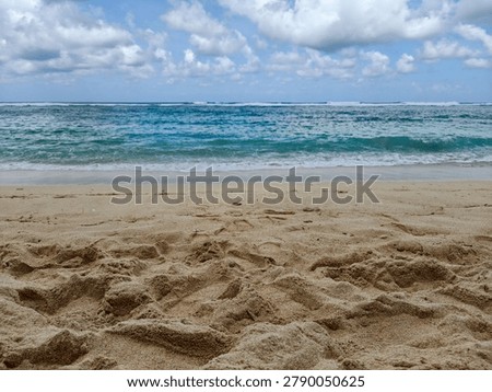 Low angle view of sandy tropical beach with turquoise ocean water under cloudy blue sky