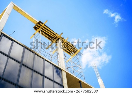 Low angle view of scaffolding with formwork on a shopping mall construction site against a blue sky with clouds. 