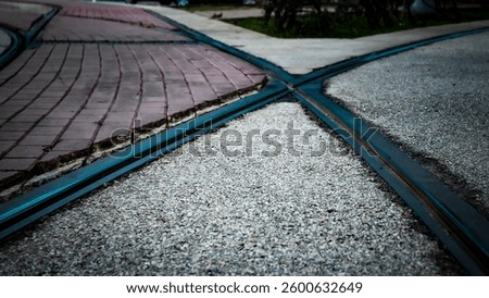 low angle view section of tracks intersecting on a street. brick cobblestone pattern and concrete pavement blocks with metal dissecting sections. X crossing background formed. at a Crossroads metaphor