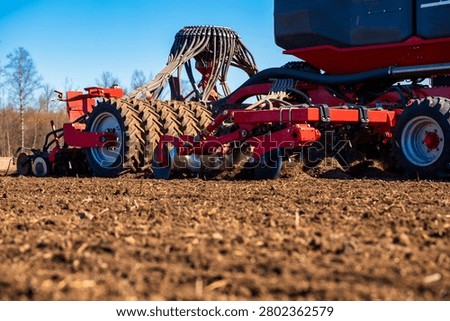 Low angle view shows a modern air seeder and cultivator at dawn in an open field, leafless trees beyond, crisp light, disc openers, gauge wheels, and hydraulic linkages.