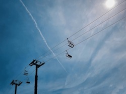 A Low Angle View Of A Ski Chairlift On A Mountain With Blue Sky