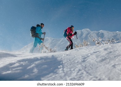 Low angle view of ski touring couple hiking up in mountains.