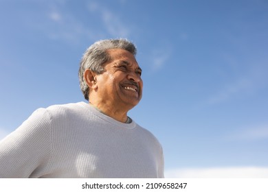 Low angle view of smiling biracial senior man looking away at beach against blue sky on sunny day. active lifestyle and weekend. - Powered by Shutterstock