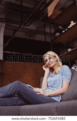 low angle view of smiling middle aged woman in earphones using smartphone 