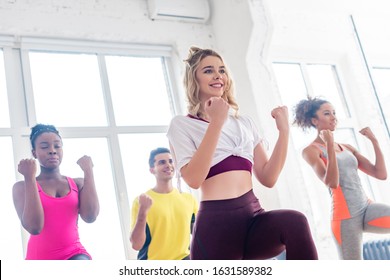 Low angle view of smiling multicultural dancers performing zumba together in dance studio