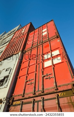 Low angle view of a stack of red shipping containers against blue sky