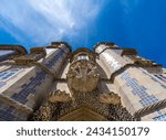 Low angle view of the Statue of Triton on a shell with decorative stone carving that guards the entrance to the Pena Palace, with the towers decorated with Portuguese mosaics. Sintra. Portugal.