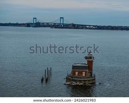 Low Angle view of the Stepping Stones Light, built in a Victorian-style in the Long Island Sound, NY. The Throgs Neck Bridge is in the distance, taken on a cloudy day.