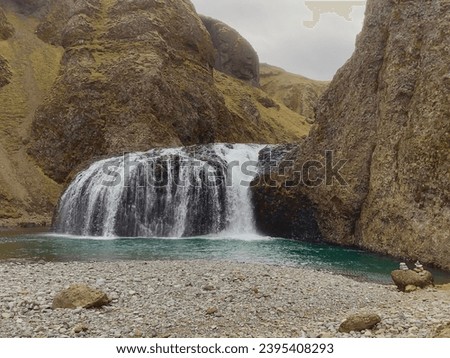 Low angle view of the Stjornarfoss waterfall and cairns on a rock