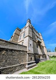 Low angle view of stone castle exterior with blue sky and green grass