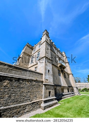 Low angle view of stone castle exterior with blue sky and green grass