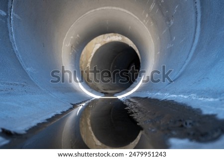 Low angle view of stormwater trickling through a large concrete culvert