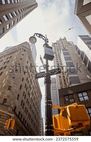 low angle view of street pole with road signs and traffic lights near tall building in new york city