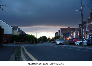 Low Angle View Of A Suburban Street With Dark Storm Clouds During Late Afternoon In Summer