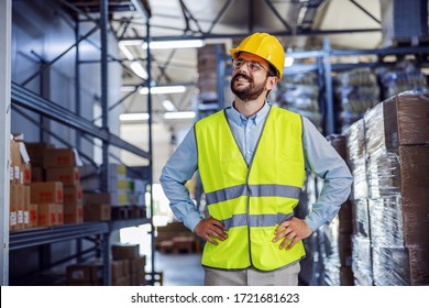 Low Angle View Of Successful Proud Businessman Standing With Hands On Hips And Looking Around His Factory.