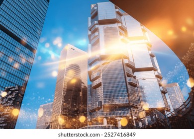 A low angle view of a tall modern skyscraper in Hong Kong. The building's glass facade reflects the bright sky and sun. - Powered by Shutterstock