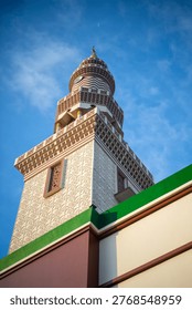Low angle view of a tall mosque minaret against a blue sky with moon crescent