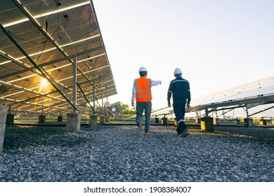 Low angle view of technician walks with investor through field of solar panels, Alternative energy to conserve the world's energy, Photovoltaic module idea for clean energy production.