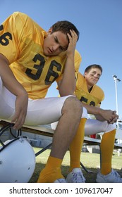 Low Angle View Of A Tense American Football Player Sitting With Teammate On Bench