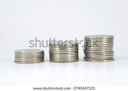 Low angle view of three aligned silver coin stacks on white background emphasizing layered edges reflective metal texture and increasing height suitable for wealth building or investment themes