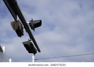 Low angle view of traffic lights hanging from a metal pole. Urban street signal against a cloudy blue sky.