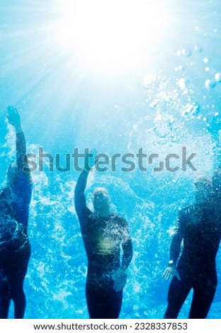 Low angle view triathletes in wetsuits underwater