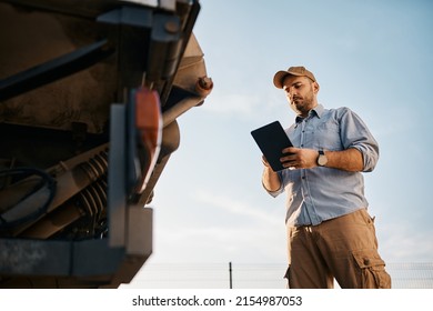 Low Angle View Of Truck Driver Using Digital Tablet Outdoors. Copy Space.