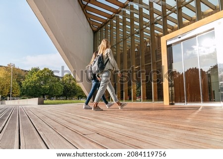 Low angle view of two females college classmates entering the university.