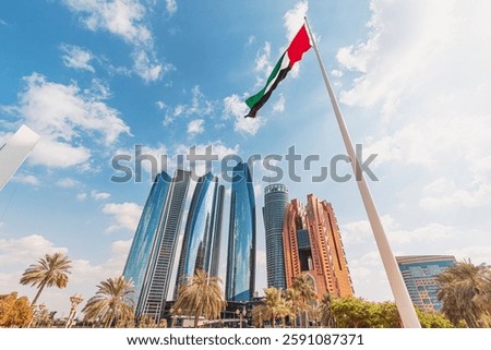 Low angle view of the UAE flag waving with modern skyscrapers on the background in Abu Dhabi