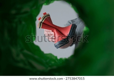 Low angle view unrecognizable man sorting vibrant shoes in a green recycling bin at home. Combating waste and inspiring conscious consumerism in the footwear industry